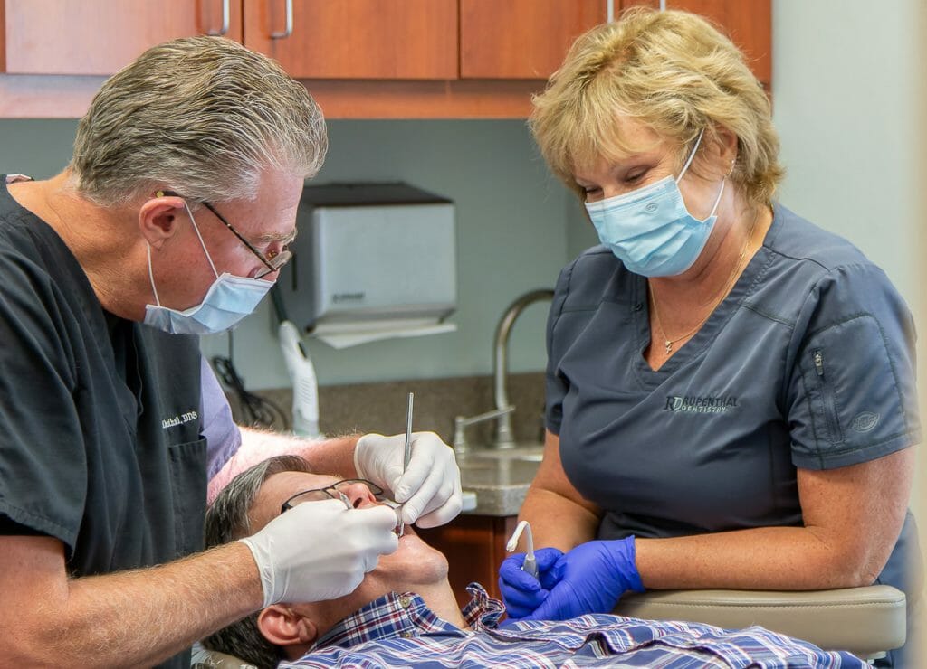 dentist and assistant help patient